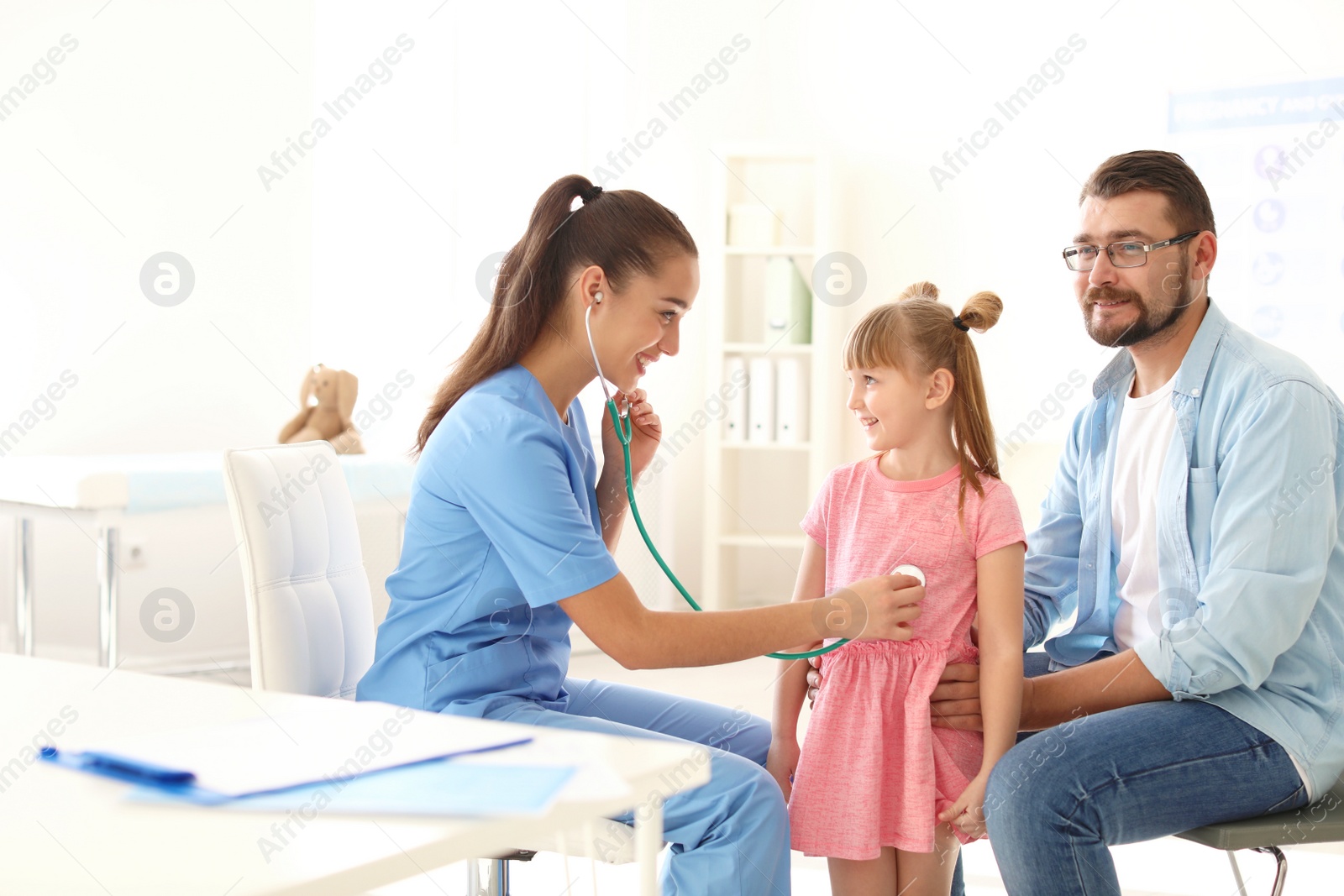 Photo of Children's doctor examining little girl with stethoscope in hospital