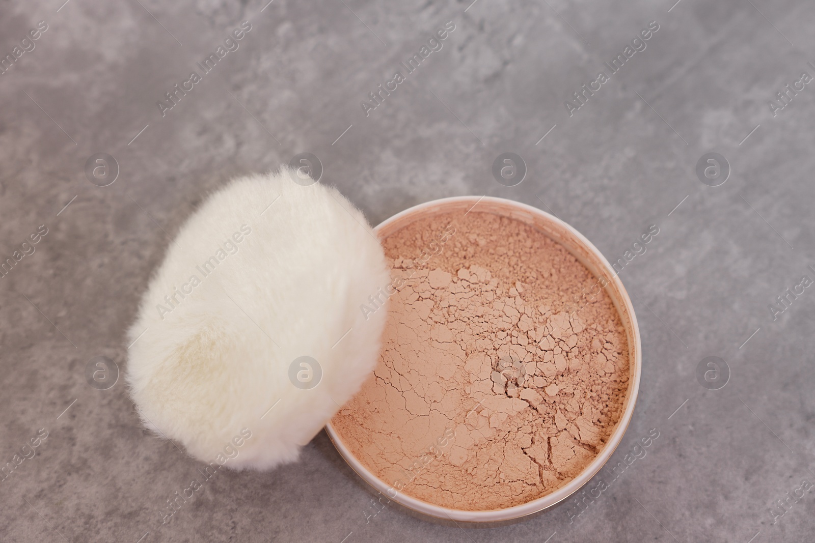 Photo of Face powder with puff applicator on grey textured table, top view