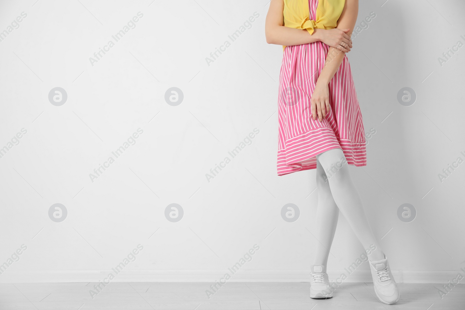 Photo of Woman wearing tights near white wall, closeup. Space for text