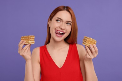 Young woman with pieces of tasty cake on purple background