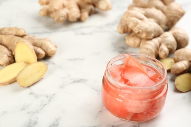 Photo of Spicy pickled ginger and root on white marble table, space for text