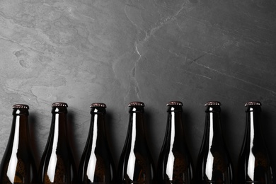 Photo of Bottles of beer on grey table, flat lay. Space for text