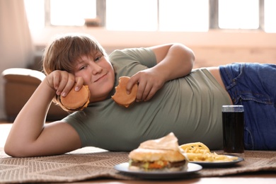 Photo of Overweight boy with fast food at home
