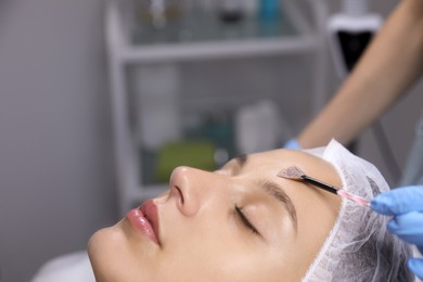 Photo of Cosmetologist applying chemical peel product on client's face in salon