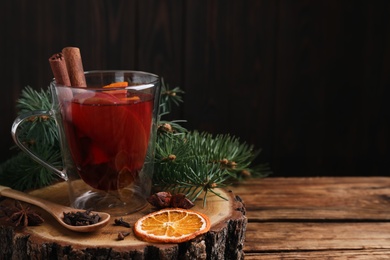 Photo of Tasty aromatic mulled wine on wooden table, space for text