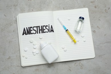 Photo of Notebook with word Anesthesia and different drugs on light table, top view