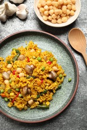 Photo of Delicious rice pilaf with vegetables served on grey table, flat lay