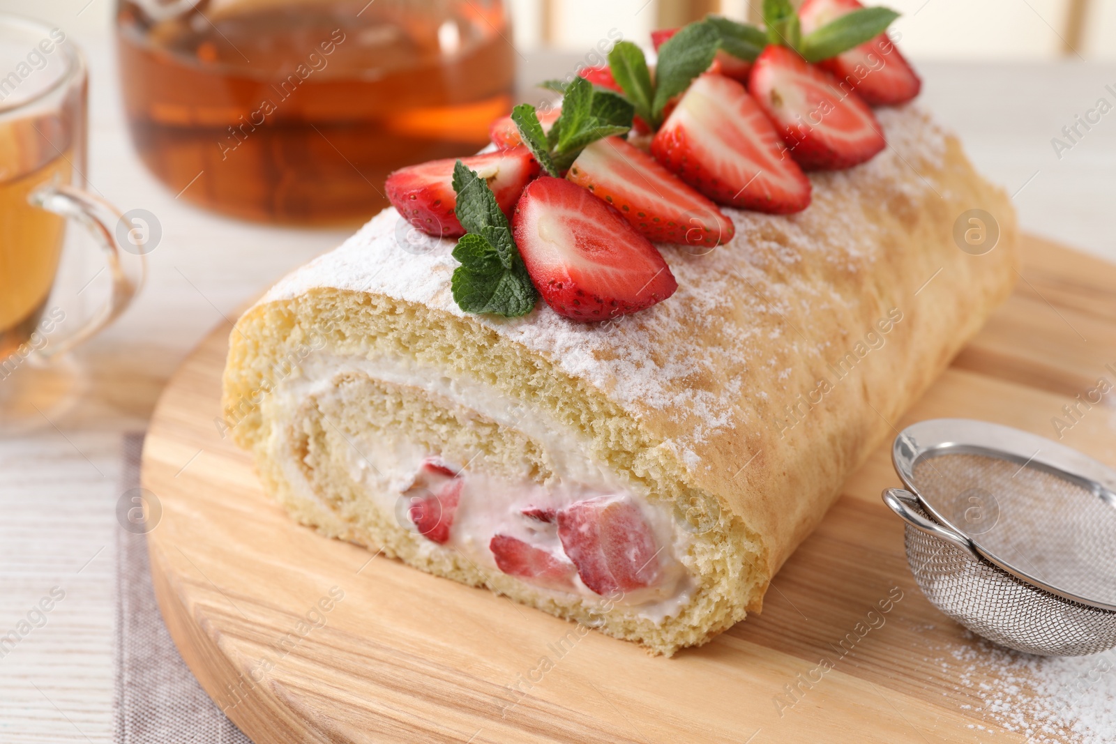 Photo of Delicious cake roll with strawberries and cream on wooden board, closeup