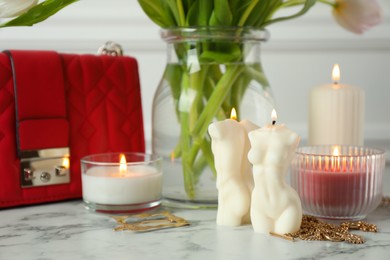 Photo of Beautiful female and male body shaped candles on white marble table. Stylish decor