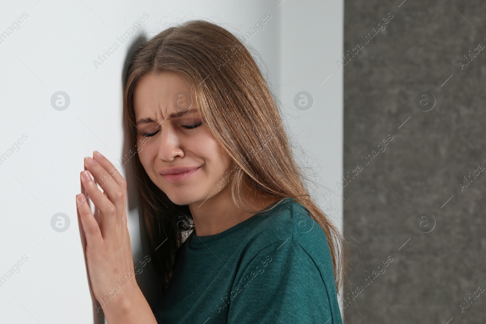 Photo of Portrait of crying young woman near light wall. Stop violence