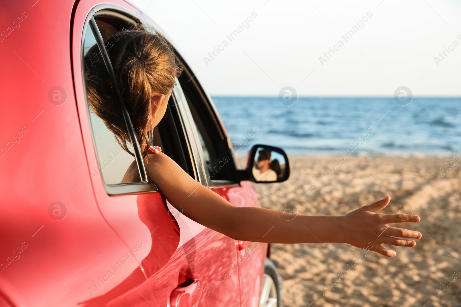 Photo of Little girl leaning out of car window on beach. Summer trip