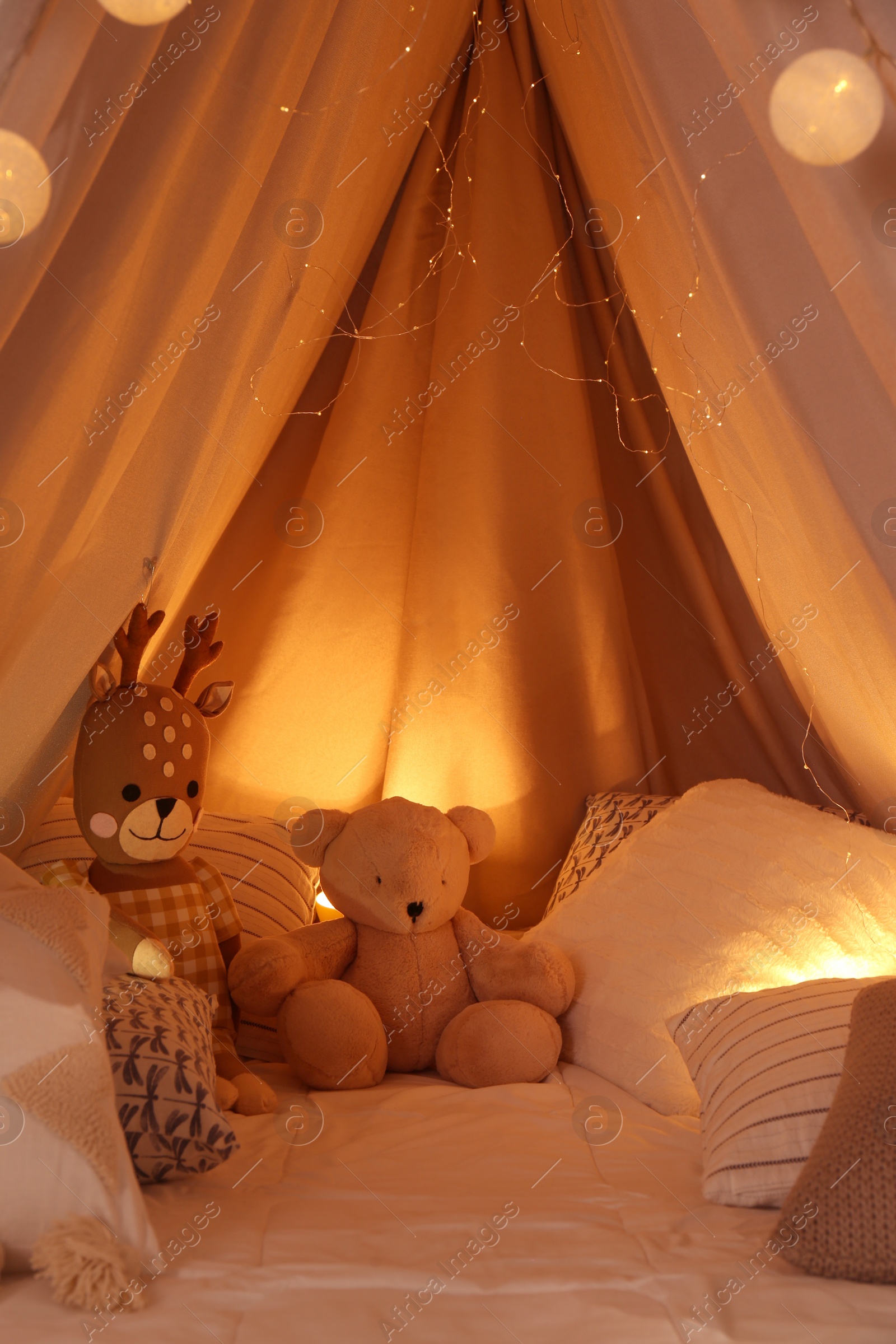 Photo of Play tent with toys and pillows indoors, closeup. Modern children's room interior