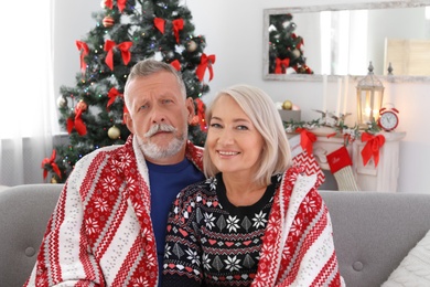 Photo of Happy mature couple with plaid at home. Christmas celebration