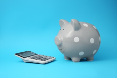 Photo of Piggy bank and calculator on light blue background