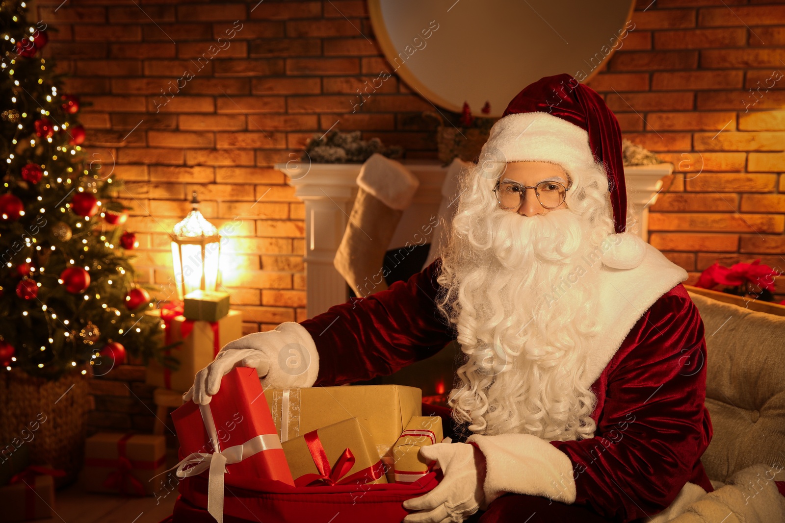 Photo of Santa Claus with sack of gifts in festively decorated room