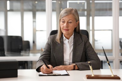 Photo of Beautiful woman working at table in office. Lawyer, businesswoman, accountant or manager