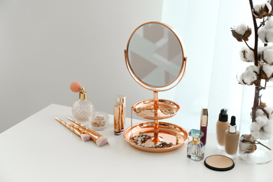 Photo of Small mirror and different makeup products on table indoors