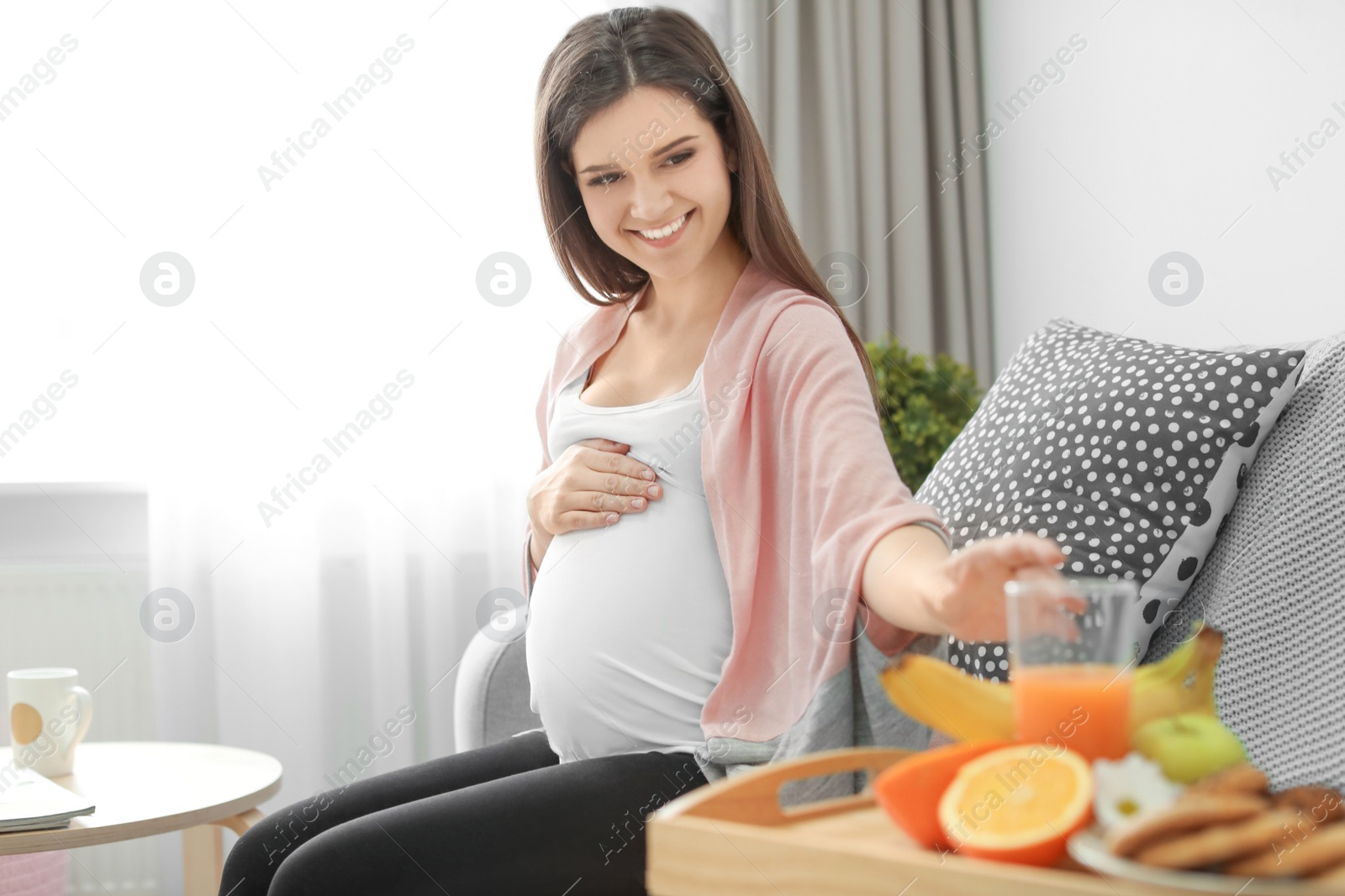 Photo of Young pregnant woman taking glass with juice at home