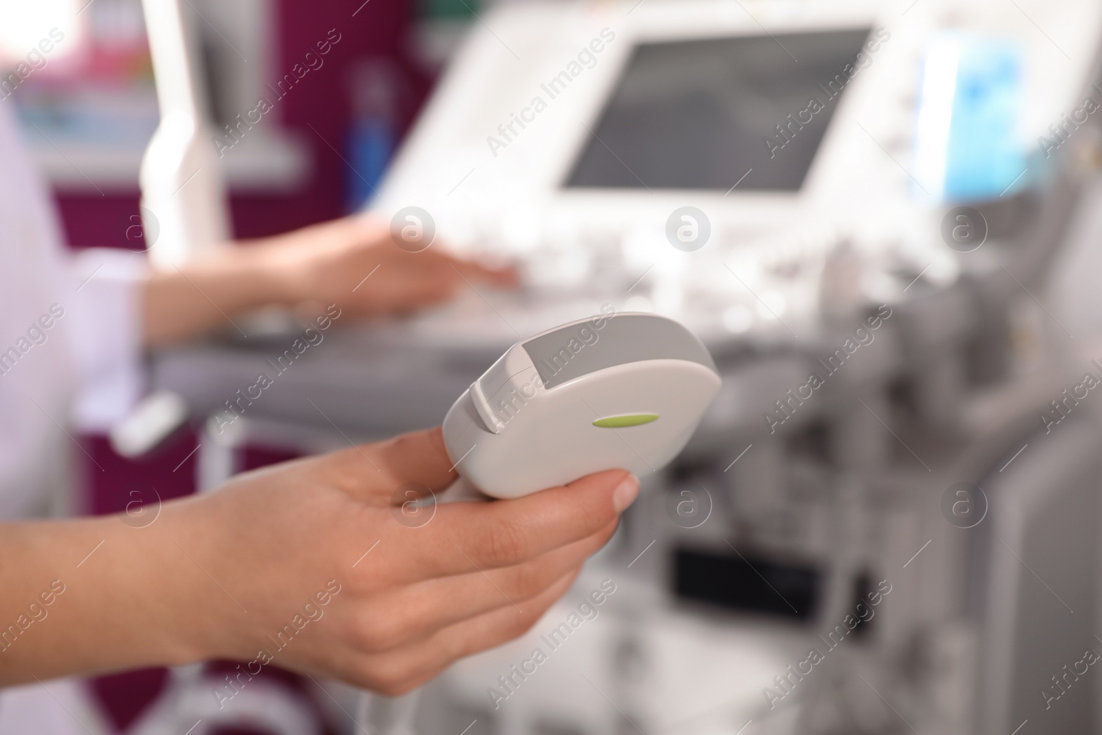 Photo of Sonographer holding ultrasound machine probe in clinic, closeup