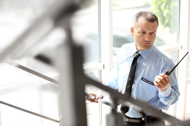 Photo of Male security guard using portable radio transmitter indoors