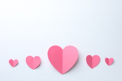 Pink paper hearts on white background, flat lay. Space for text