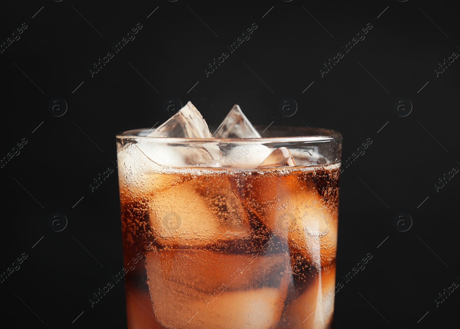 Photo of Glass of tasty refreshing cola with ice cubes on black background, closeup