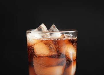 Glass of tasty refreshing cola with ice cubes on black background, closeup