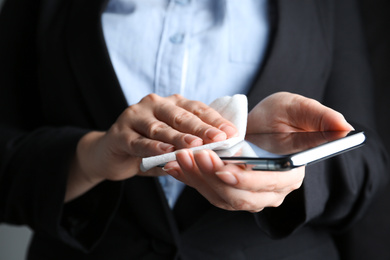 Photo of Businesswoman cleaning smartphone with antiseptic wipe, closeup