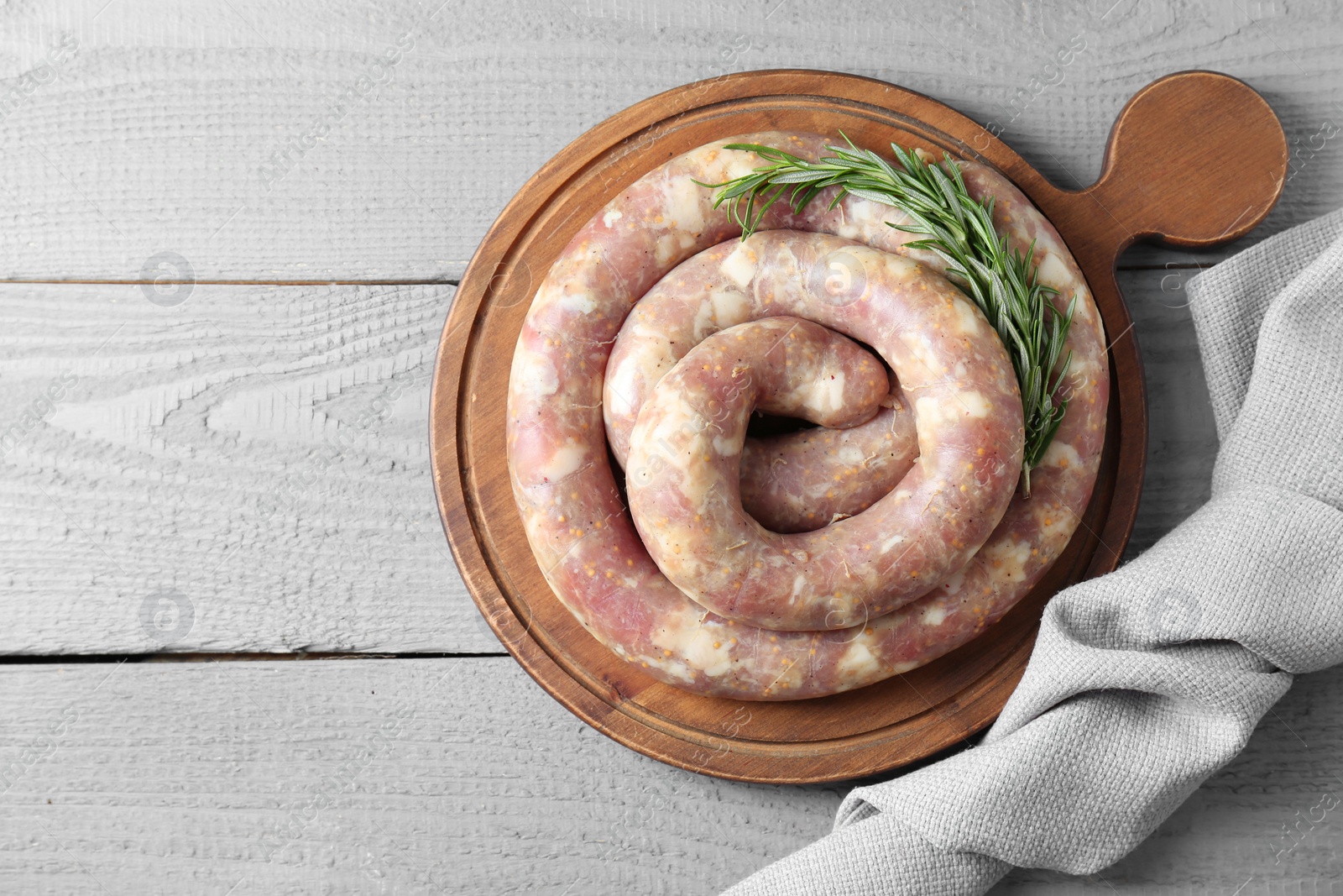 Photo of Homemade sausages and rosemary on light grey wooden table, top view. Space for text