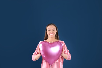 Photo of Portrait of young woman with heart shaped balloon on color background