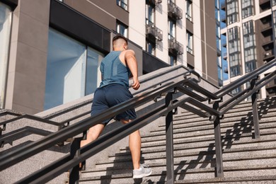 Photo of Man running up stairs outdoors on sunny day, low angle view