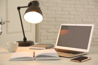 Modern laptop, smartphone, cup of coffee and notebook on white table indoors. Space for design