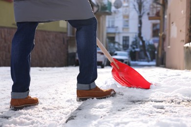 Photo of Man shoveling snow outdoors on sunny day, closeup