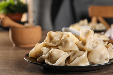 Photo of Tasty dumplings with butter on wooden table against blurred background