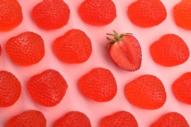 Photo of Delicious gummy candies and fresh strawberry on pink background, flat lay