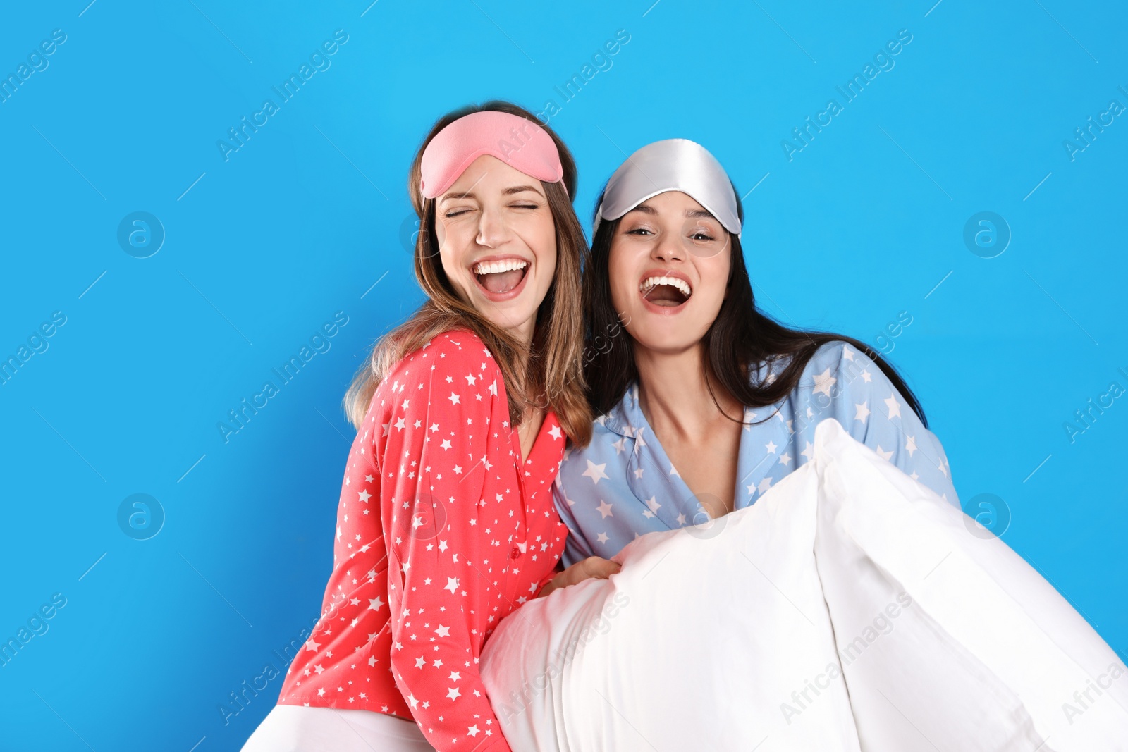 Photo of Beautiful women with pillows on light blue background. Bedtime