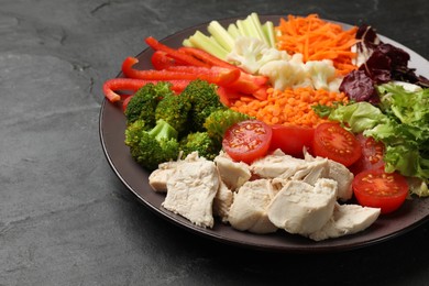 Balanced diet and healthy foods. Plate with different delicious products on black table, closeup