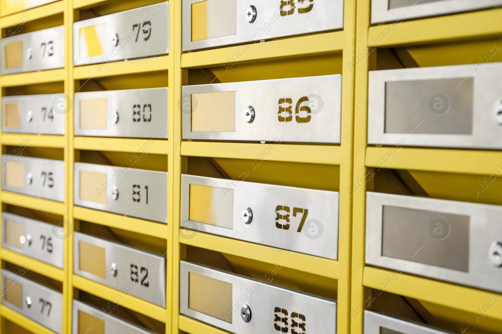 Photo of Many closed metal mailboxes with keyholes and numbers in post office, closeup