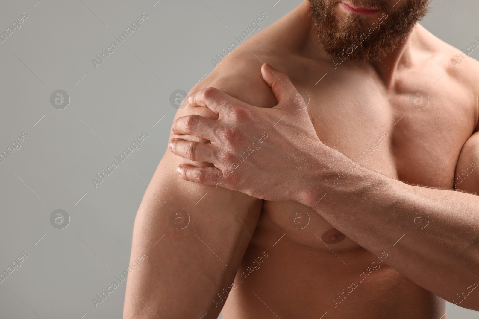 Photo of Man with muscular body on light grey background, closeup. Space for text