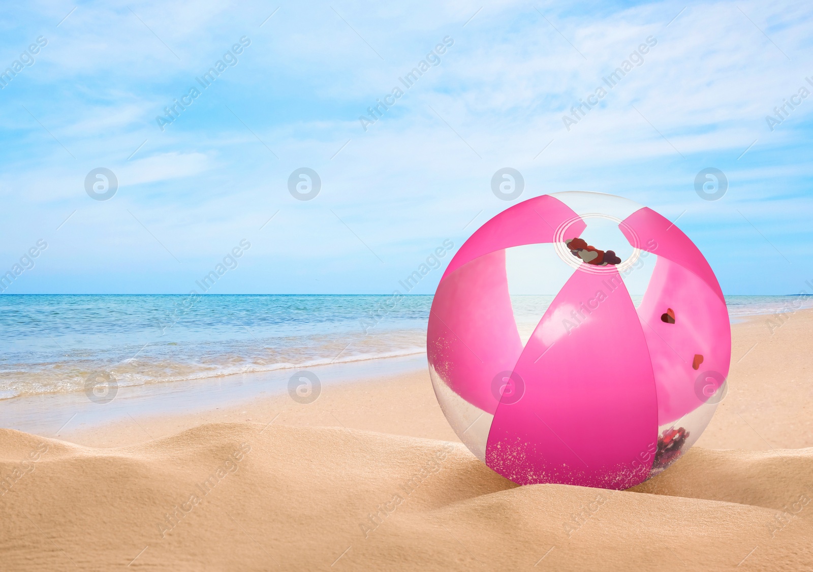 Image of Pink beach ball on sandy coast near sea, space for text 