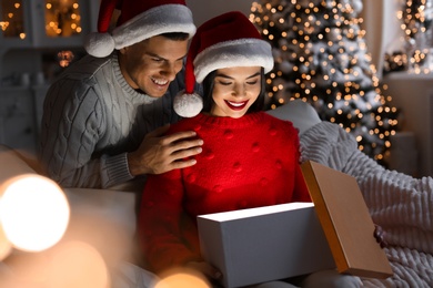 Photo of Happy couple opening magic gift box at home. Christmas celebration