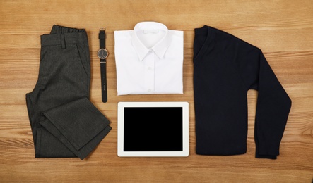 Photo of School uniform for boy and tablet on wooden background, top view