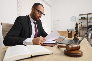Photo of Confident lawyer working with document at table in office
