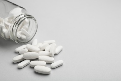 Vitamin pills and bottle on grey background, closeup. Space for text