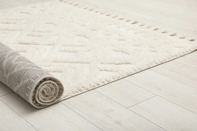Rolled white carpet with beautiful pattern on floor, closeup. Space for text