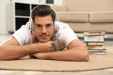Man with headphones connected to book
on floor at home. Audiobook concept