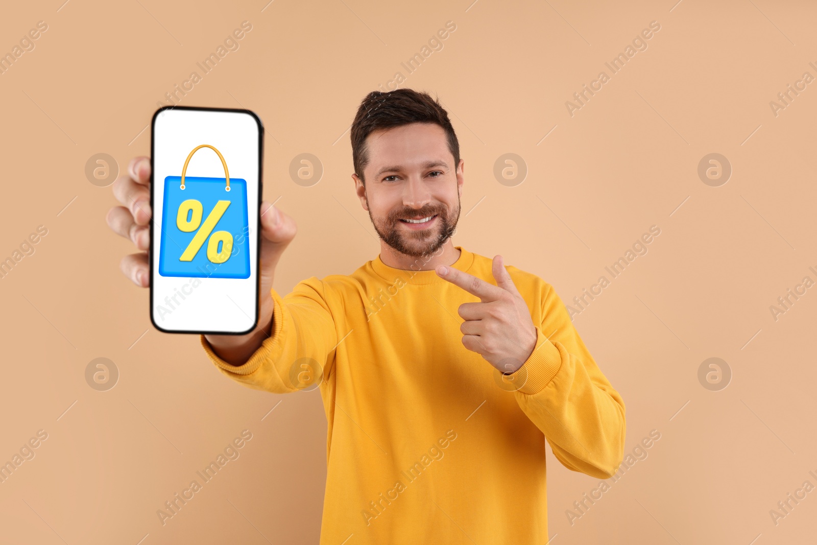 Image of Discount, offer, sale. Man pointing at mobile phone with illustration of bag and percent sign on screen, beige background