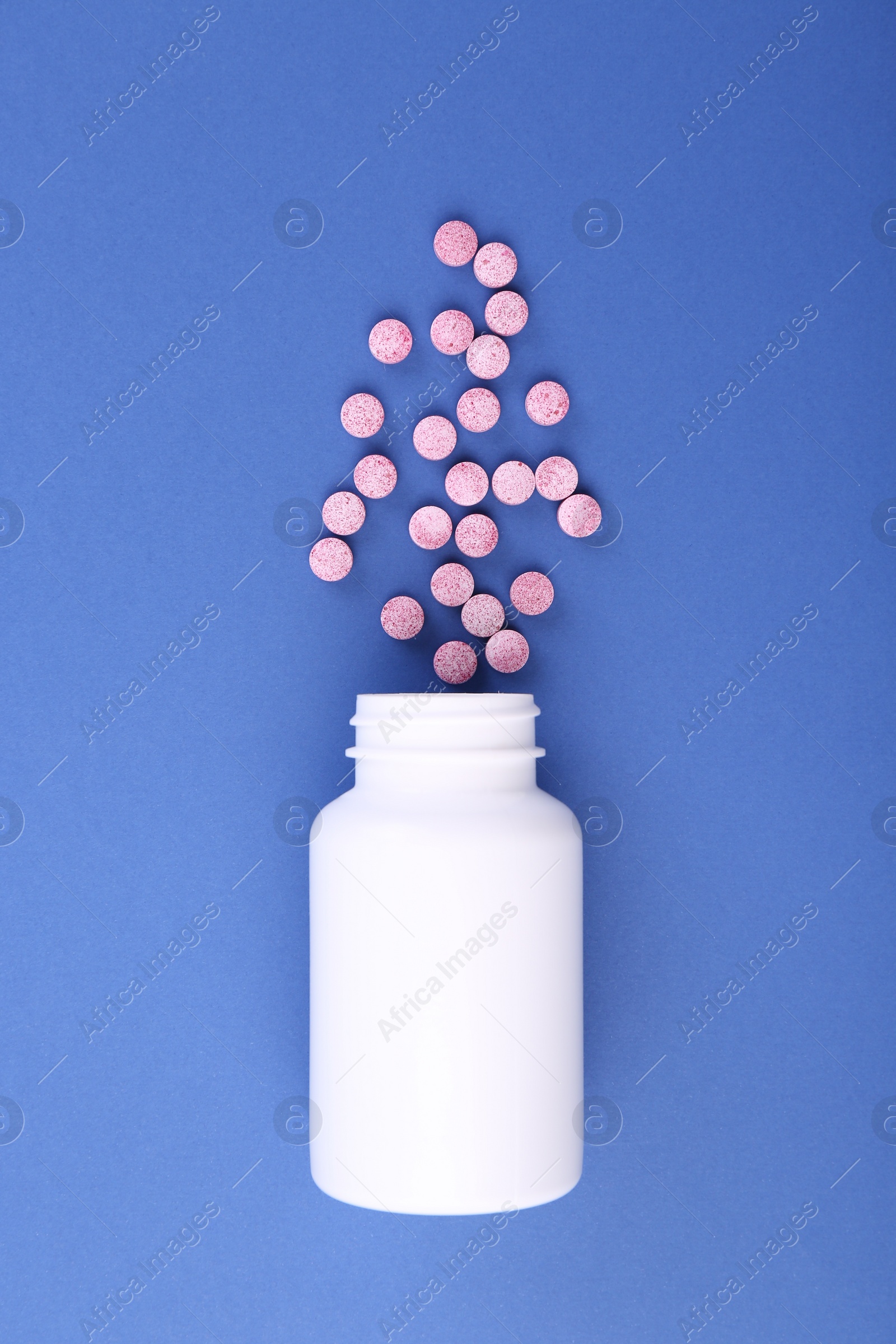 Photo of Bottle and vitamin pills on blue background, top view