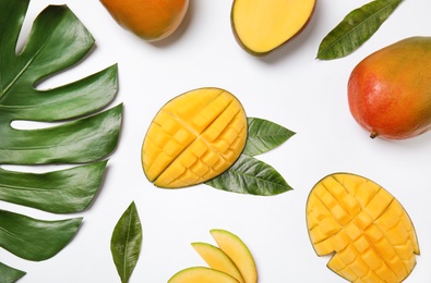 Photo of Fresh mango and green leaves on white background, flat lay