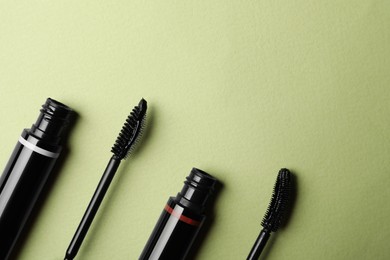 Photo of Different mascaras on light background, flat lay with space for text. Makeup product